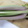 Close-up of Purple Top White Globe turnip stems resting on a cutting board, showing thick, smooth stalks with pale green and purple coloration near the crown.